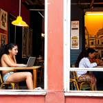 A bustling, vibrant cafe in Mexico City's Roma Norte district, where a young digital nomad sits with a laptop, immersed in work. Sunlight filters through large windows, illuminating stylish colonial architecture outside. The scene should convey a blend of focused productivity, a lively urban atmosphere with diverse people, and the aesthetic charm of the neighborhood, perhaps with subtle hints of Mexican culture like a unique coffee cup or street art.